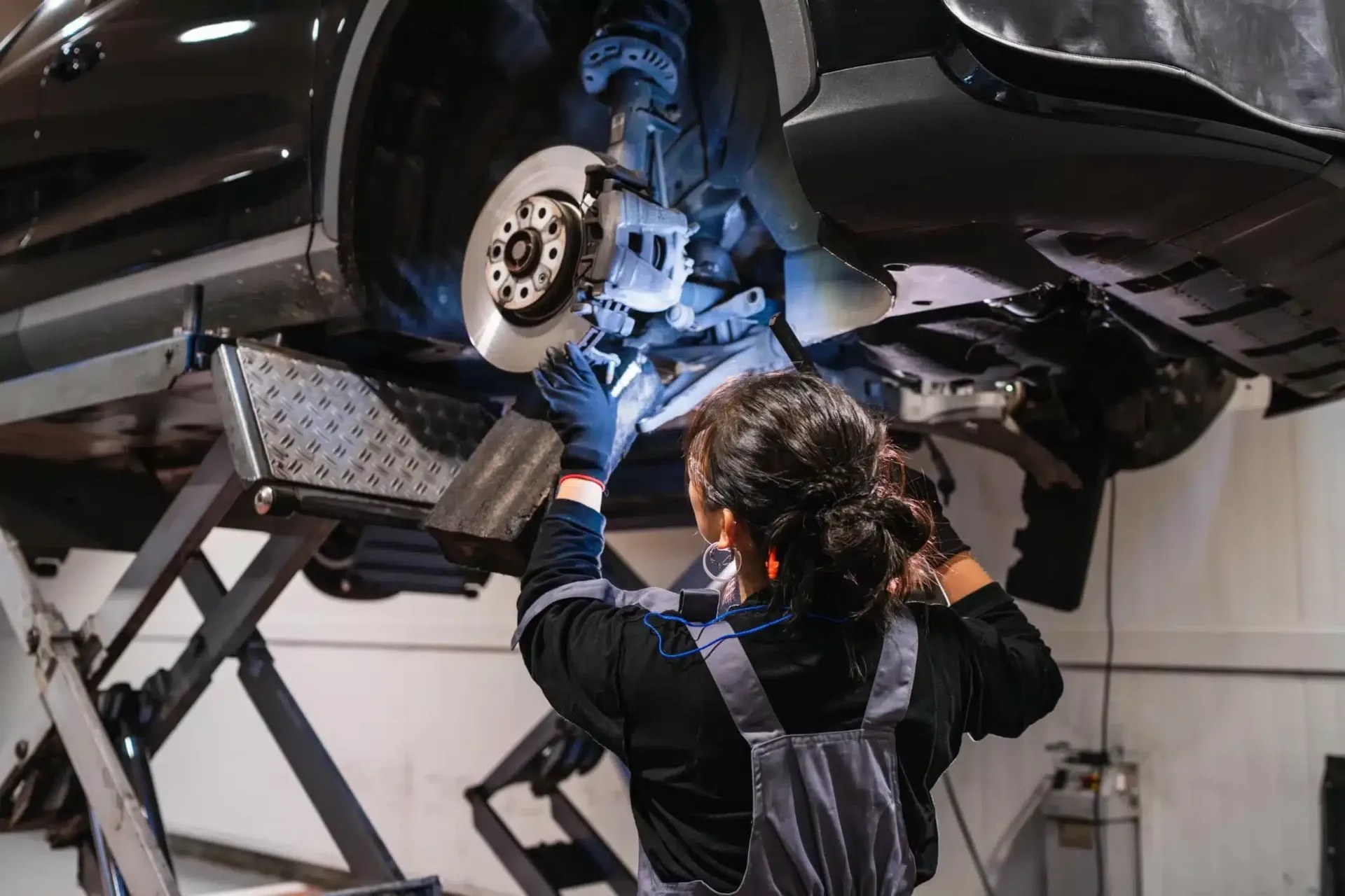 A mechanic inspecting the brake disc of a car raised on a garage lift